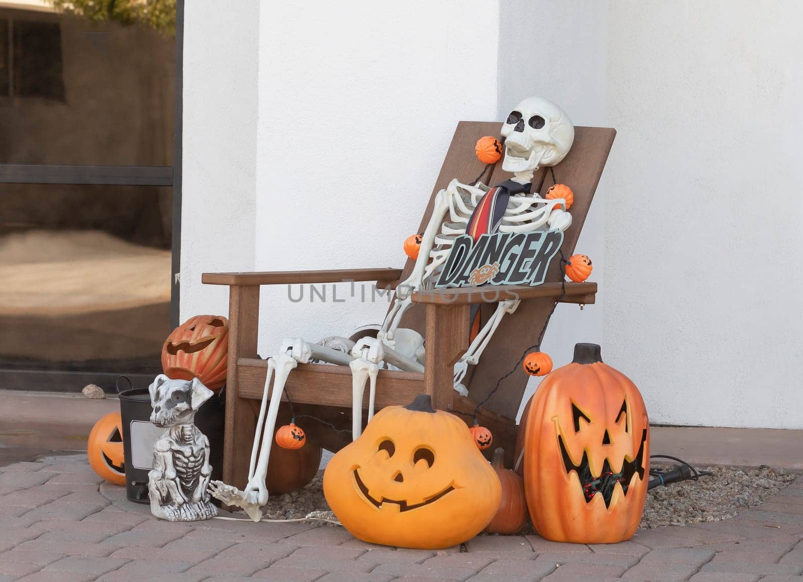 Skeleton In Chair, Pumpkins with Faces, Scary Dog And Skulls Are Traditional Attributes Of Halloween. Outdoor Decoration For Halloween Party. Horizontal Plane by netatsi