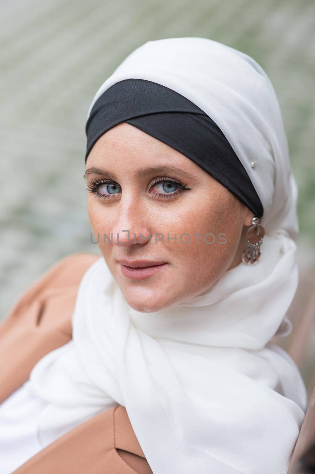 Portrait of a young blue-eyed woman in a hijab outdoors