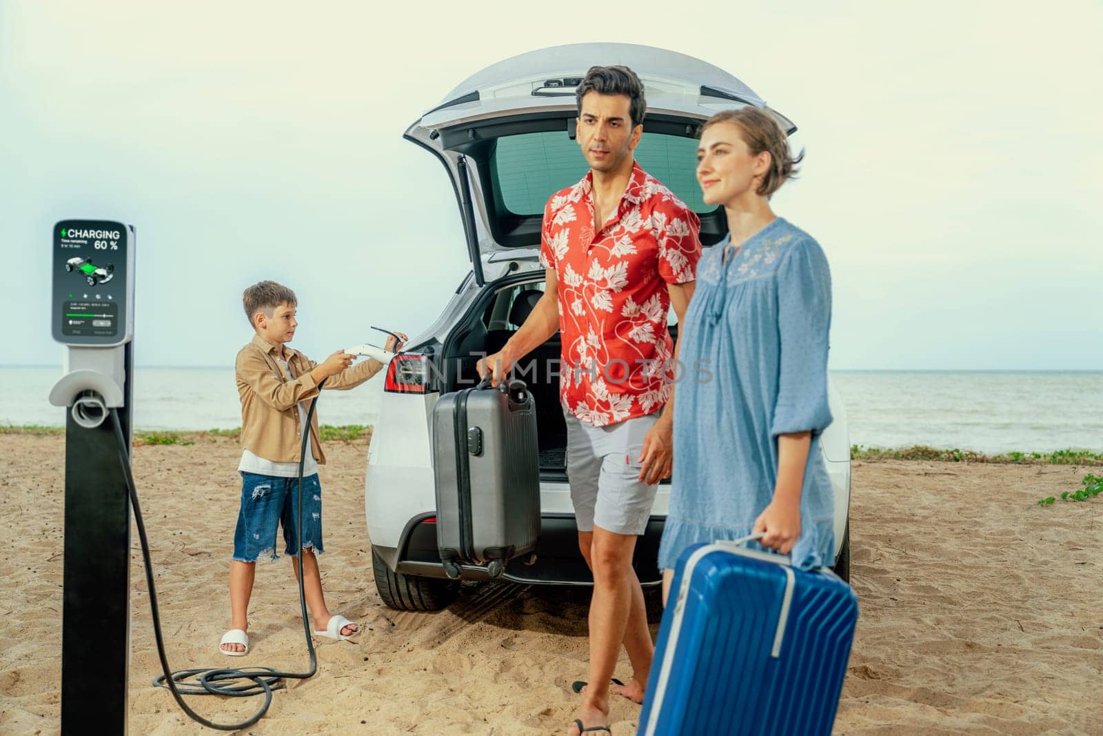 Family vacation trip traveling by the beach with electric car, lovely family taking luggage out while charging EV car battery with clean energy. Alternative family travel by eco-friendly car.Perpetual