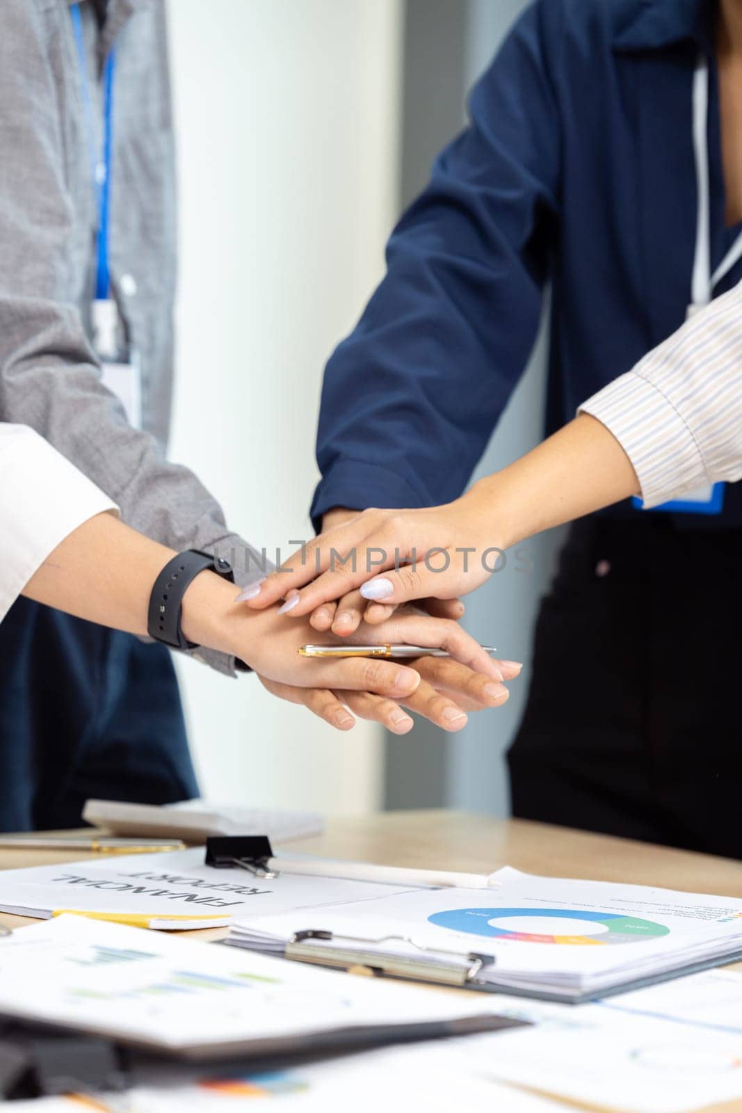 Businesspeople stack their hand on top of each other, indicating success after work meeting in conference room by itchaznong