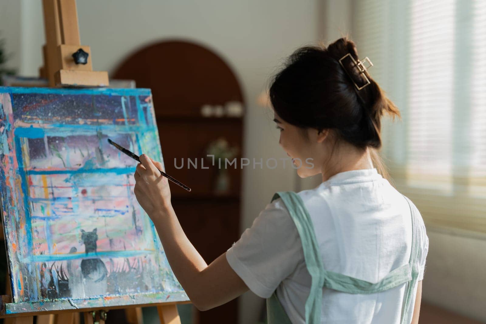 Female artist hold color palette and paintbrush for painting during hobby workshop.