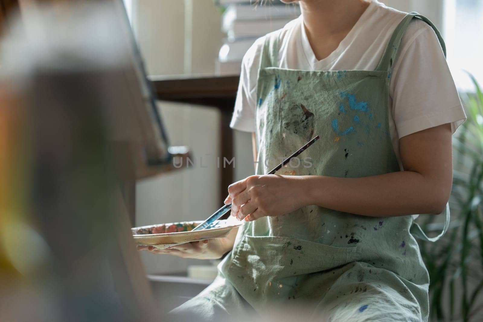 Female artist hold color palette and paintbrush for painting during hobby workshop by itchaznong