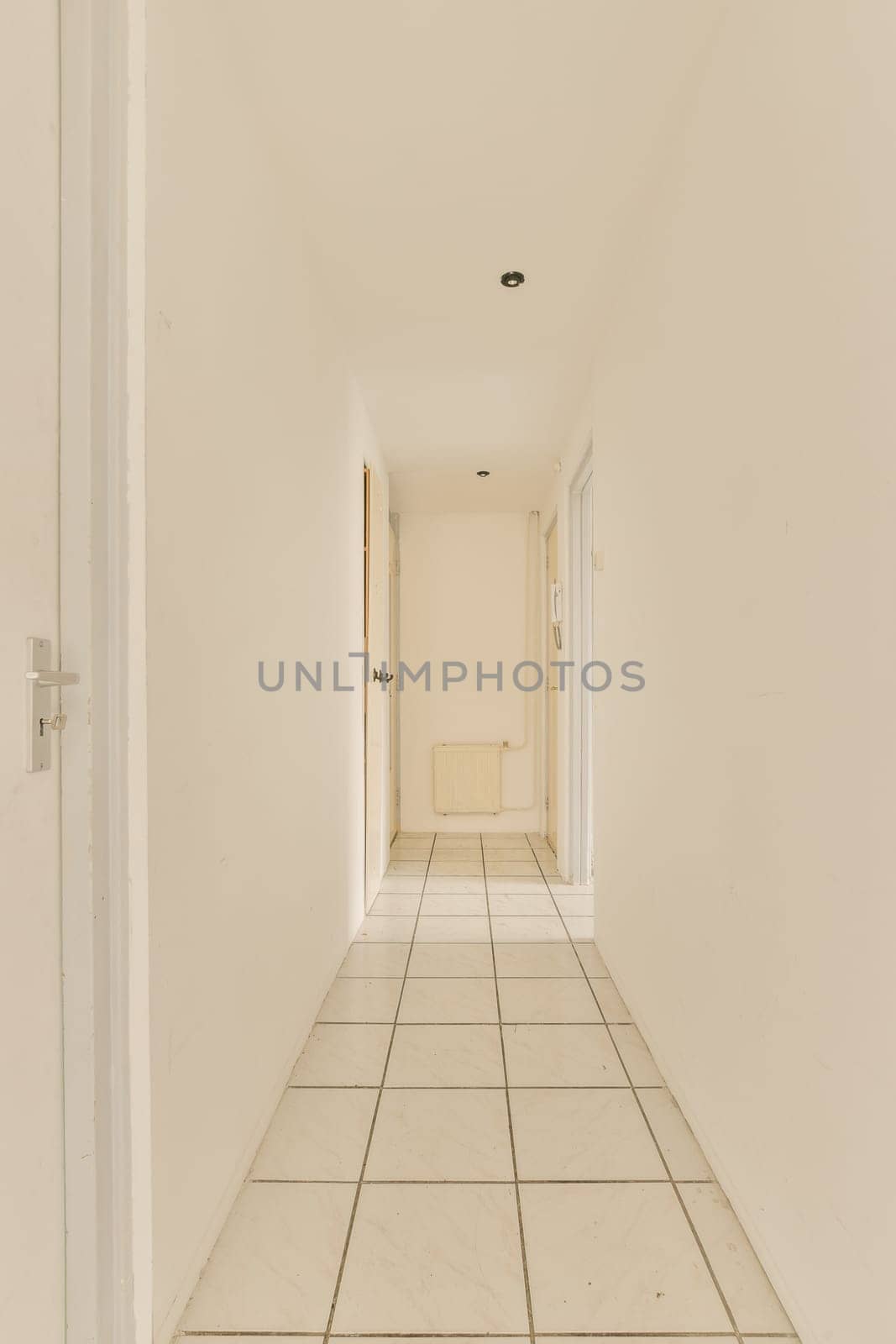 an empty hallway with white tiled floors and walls by casamedia