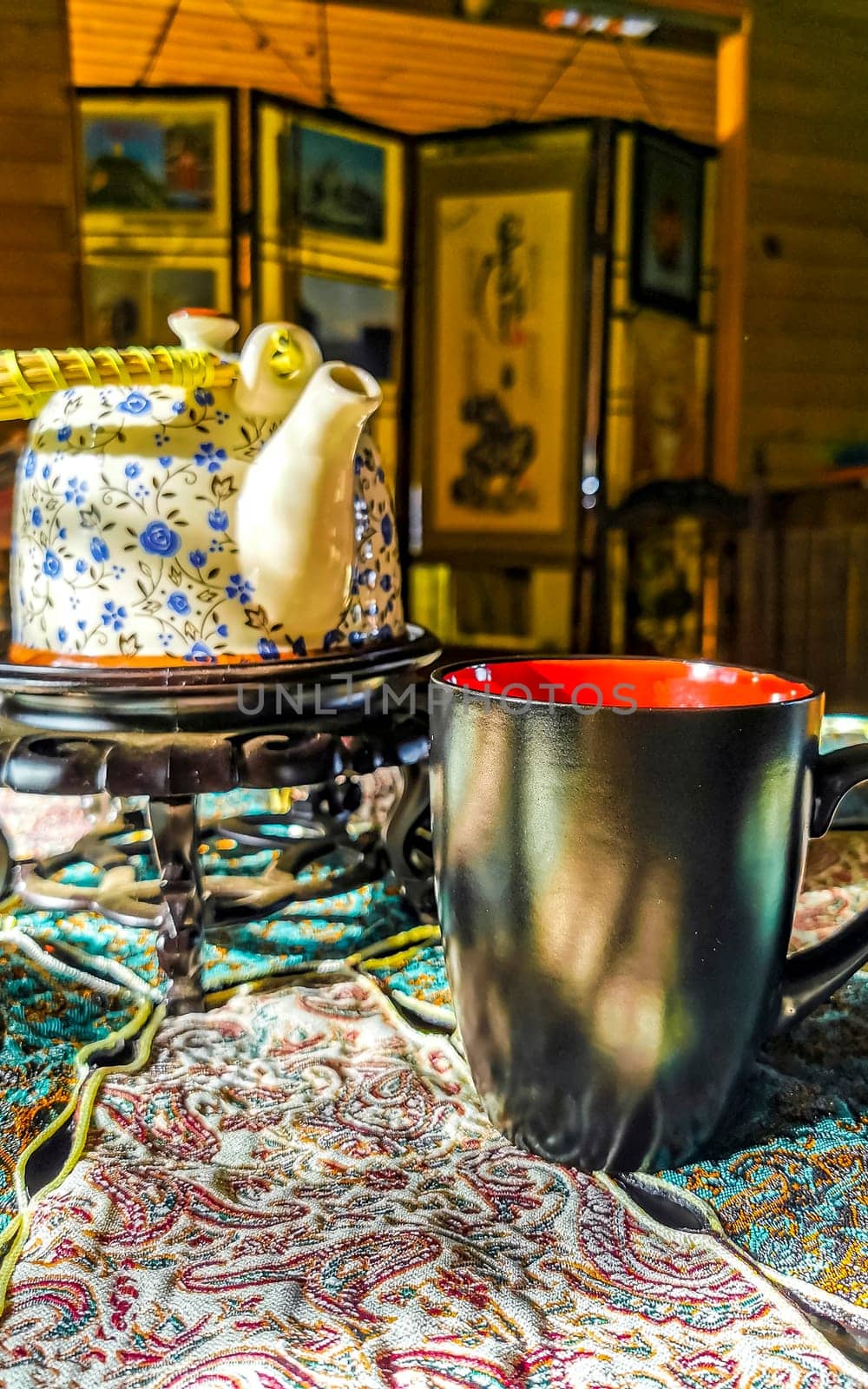 Red and black coffee cup on an elegant turquoise tablecloth. by Arkadij