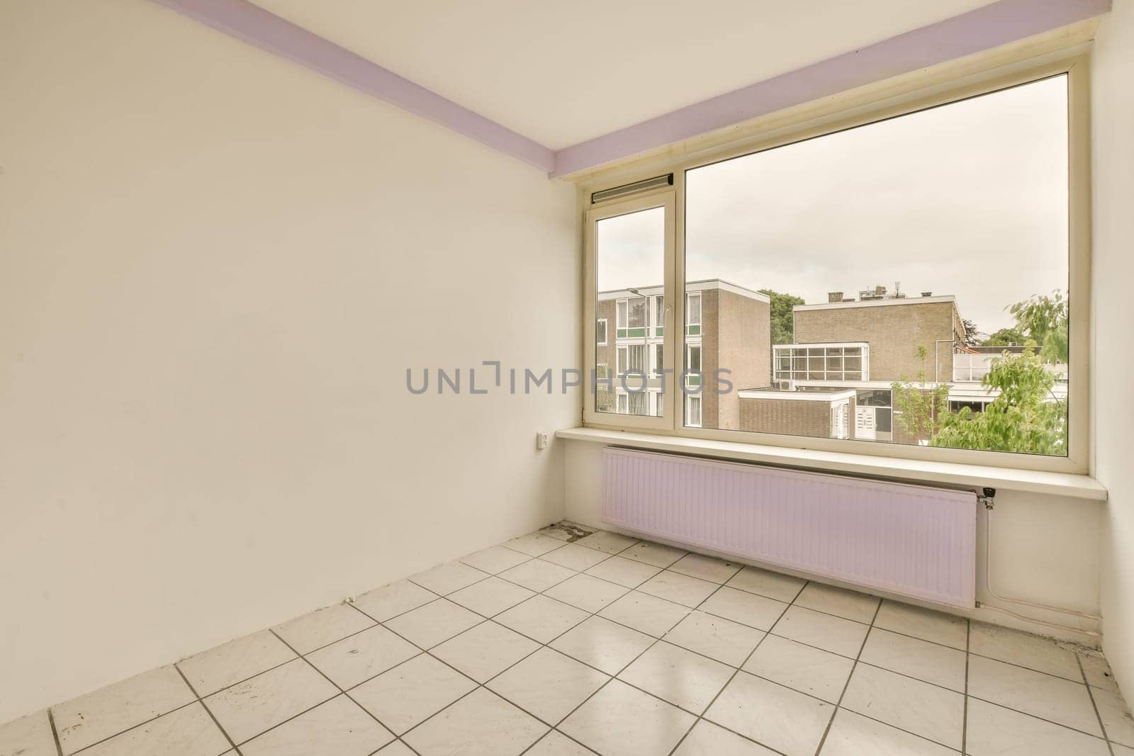 an empty room with white tiles and purple trim around the window panes, looking out onto the street below