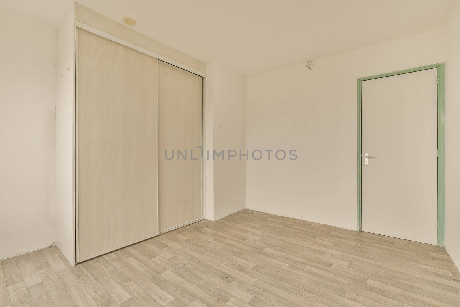 an empty room with white walls and wood flooring the door is open on the right side of the room