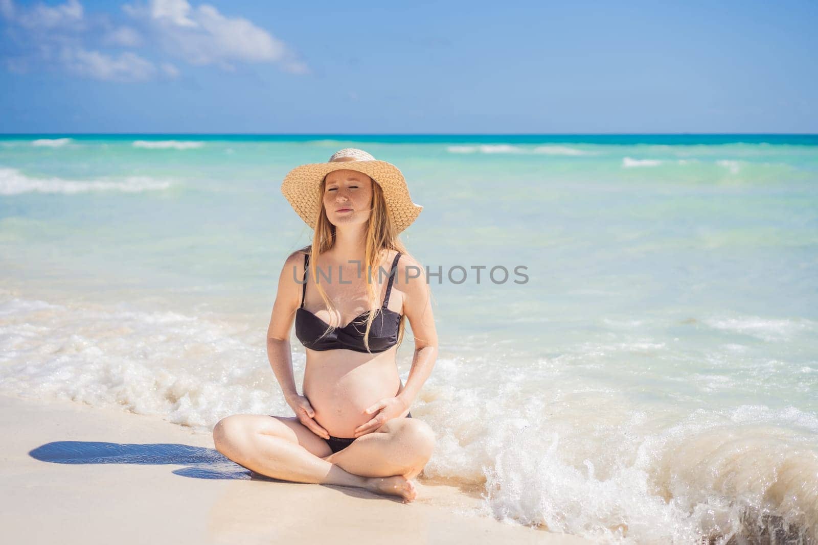 Radiant and expecting, a pregnant woman stands on a pristine snow-white tropical beach, celebrating the miracle of life against a backdrop of natural beauty.