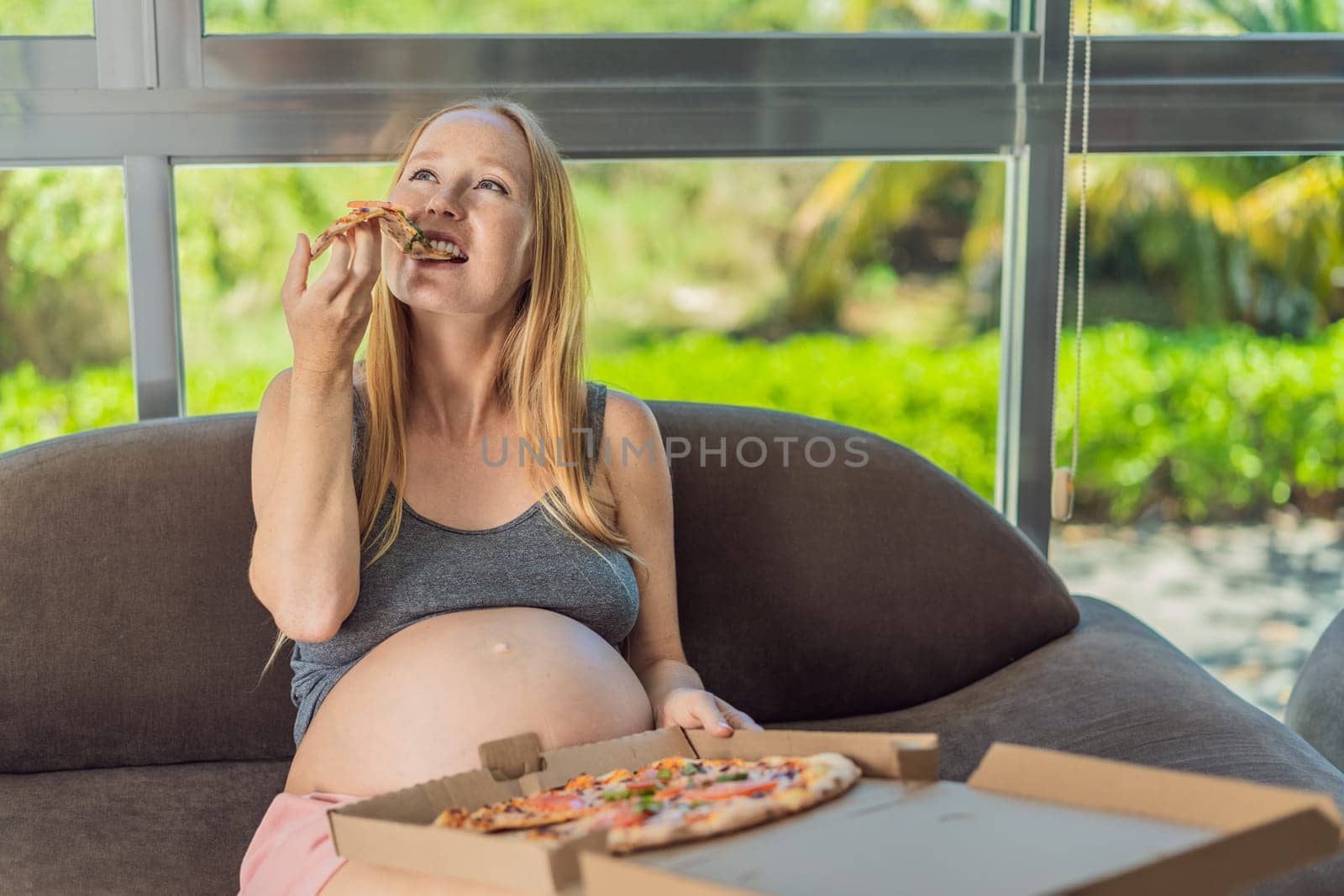 A pregnant woman enjoys a slice of pizza, savoring a moment of indulgence while satisfying her craving for a delightful, comforting treat. Excited Pregnant Young Lady Enjoying Pizza Holding Biting Tasty Slice Posing With Carton Box. Junk Food Lover Eating Italian Pizza. Unhealthy Nutrition Cheat Meal by galitskaya