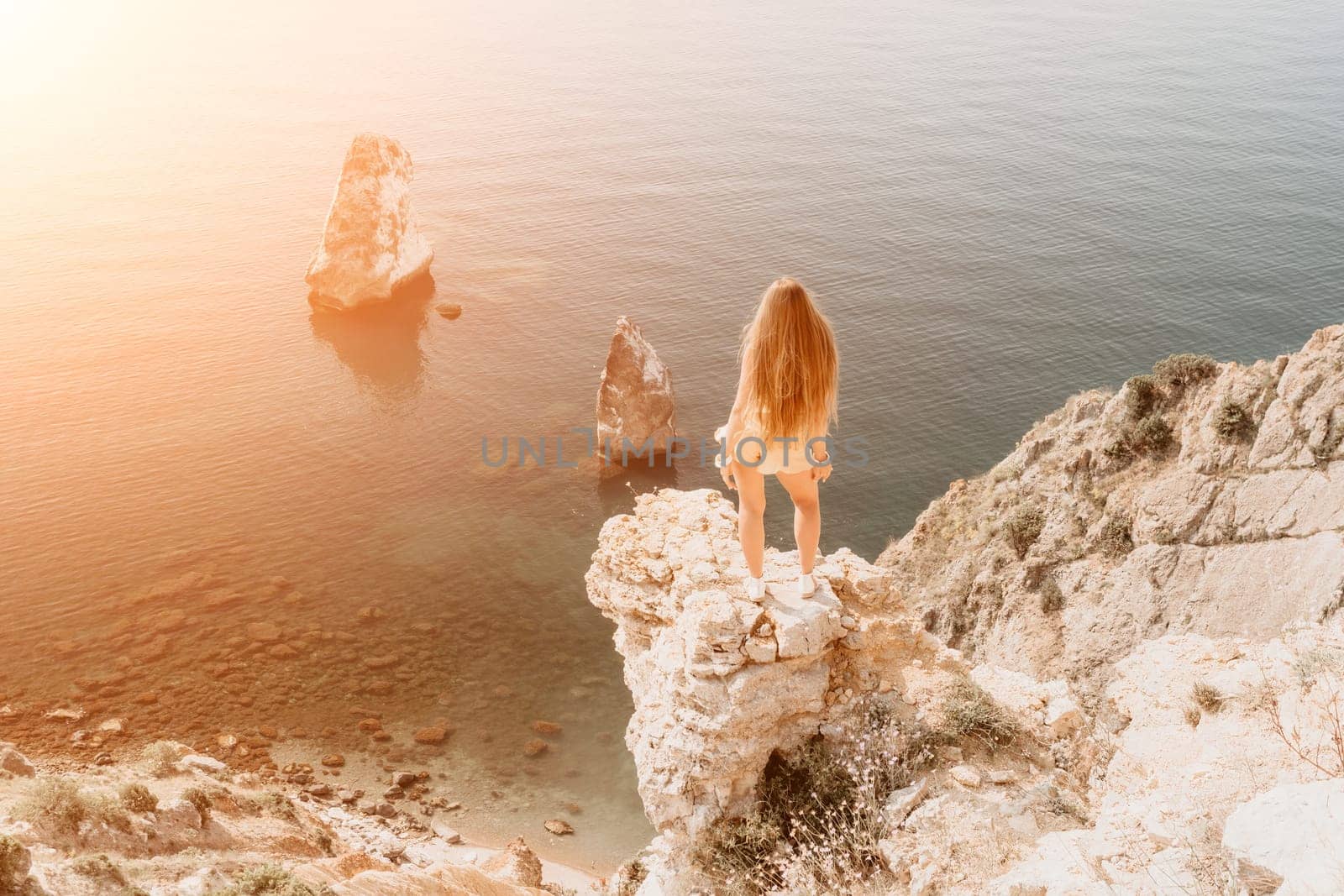 Woman travel sea. Happy tourist taking picture outdoors for memories. Woman traveler looks at the edge of the cliff on the sea bay of mountains, sharing travel adventure journey.