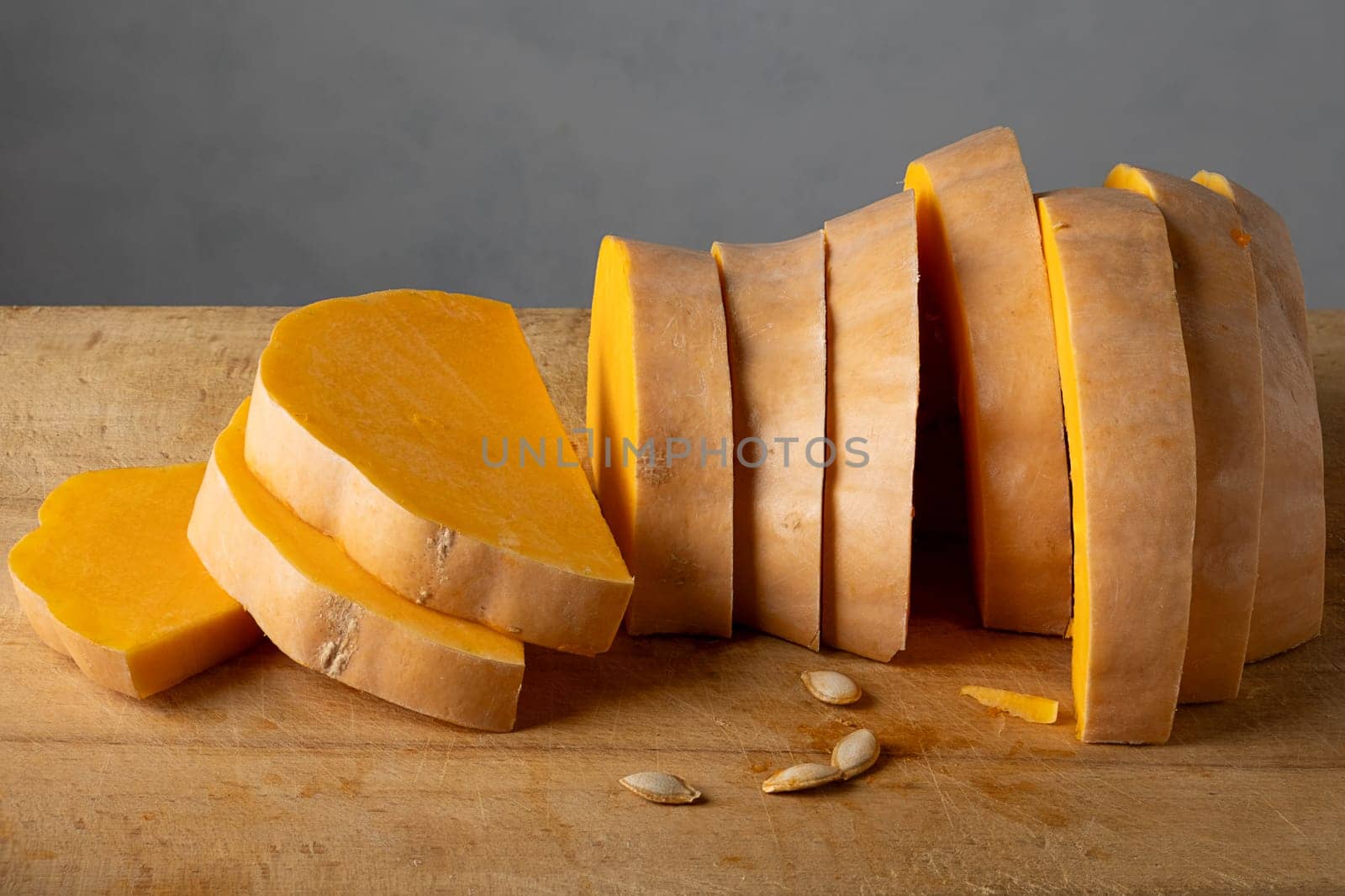 Ripe pumpkin cut into slices on a wooden cutting board for cooking.