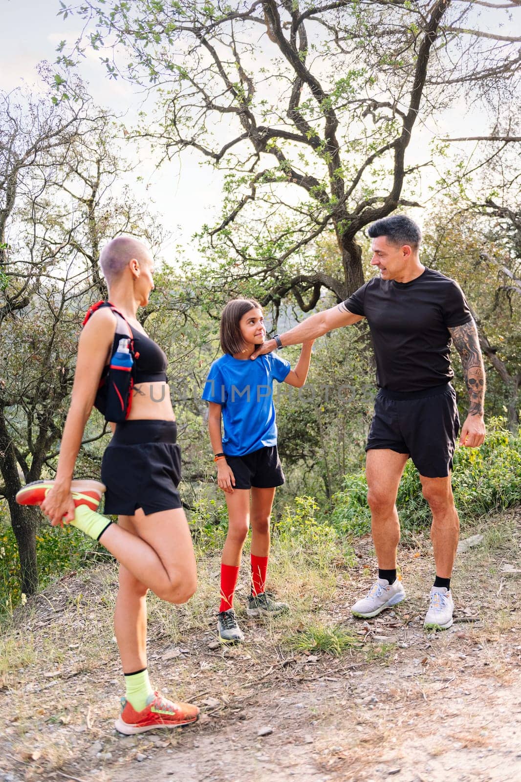 vertical photo of a family stretching and warming up for sports in the countryside, concept of sport with kids in nature and active lifestyle, copy space for text