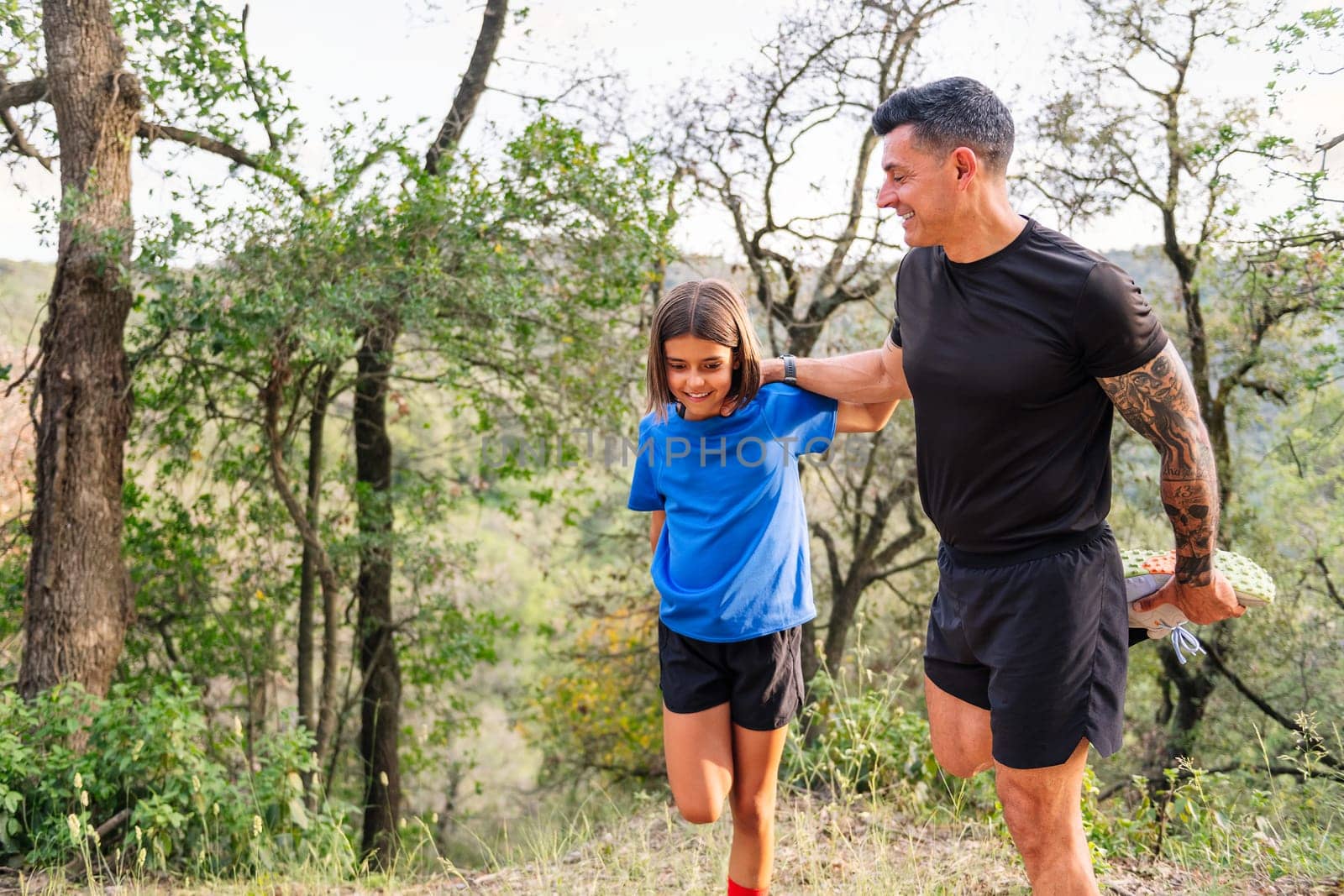 father and daughter stretching and warming up for sports in the countryside, concept of sport with kids in nature and active lifestyle, copy space for text