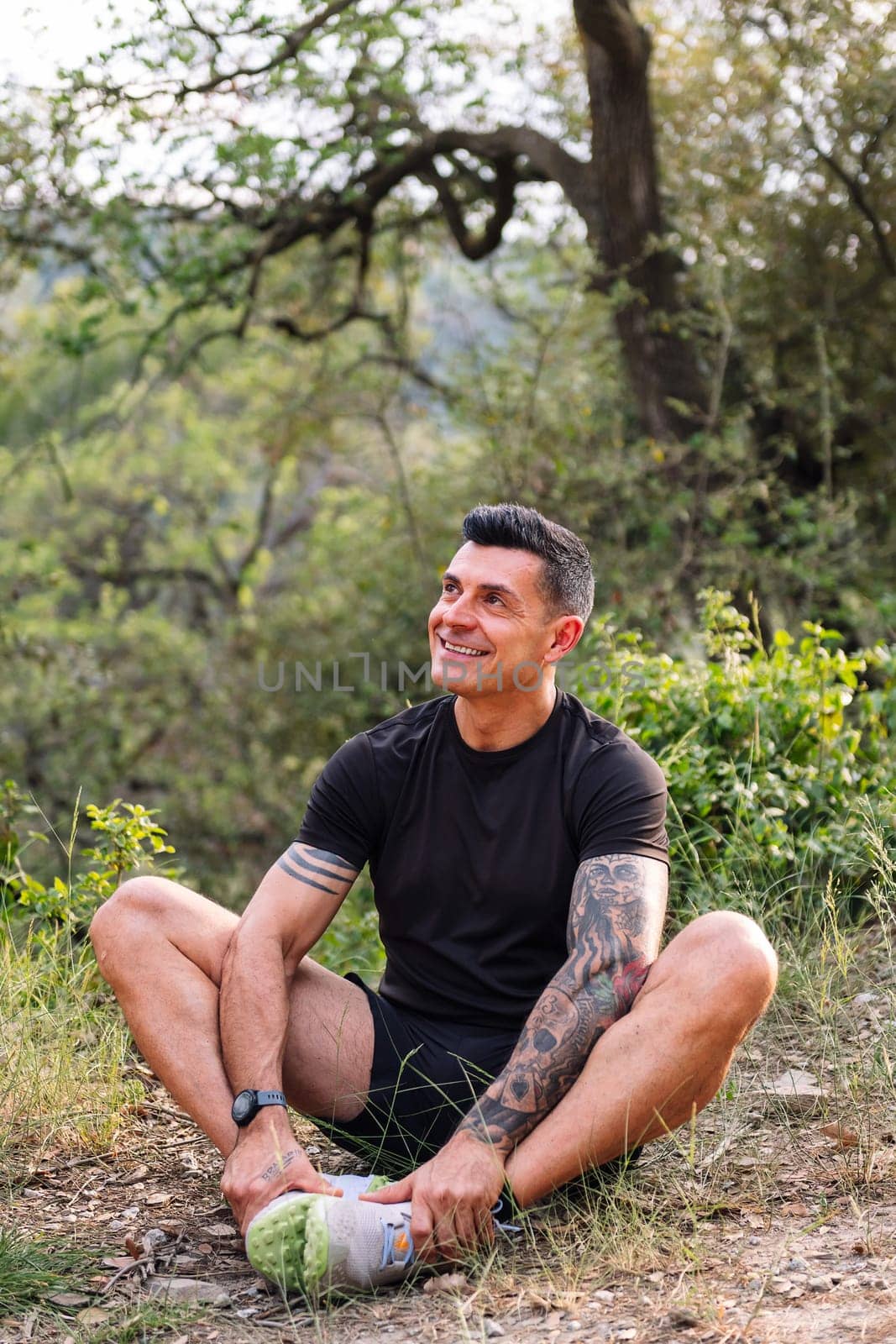 vertical photo of a man stretching and warming up legs for sports in the countryside, concept of sport in nature and active lifestyle, copy space for text