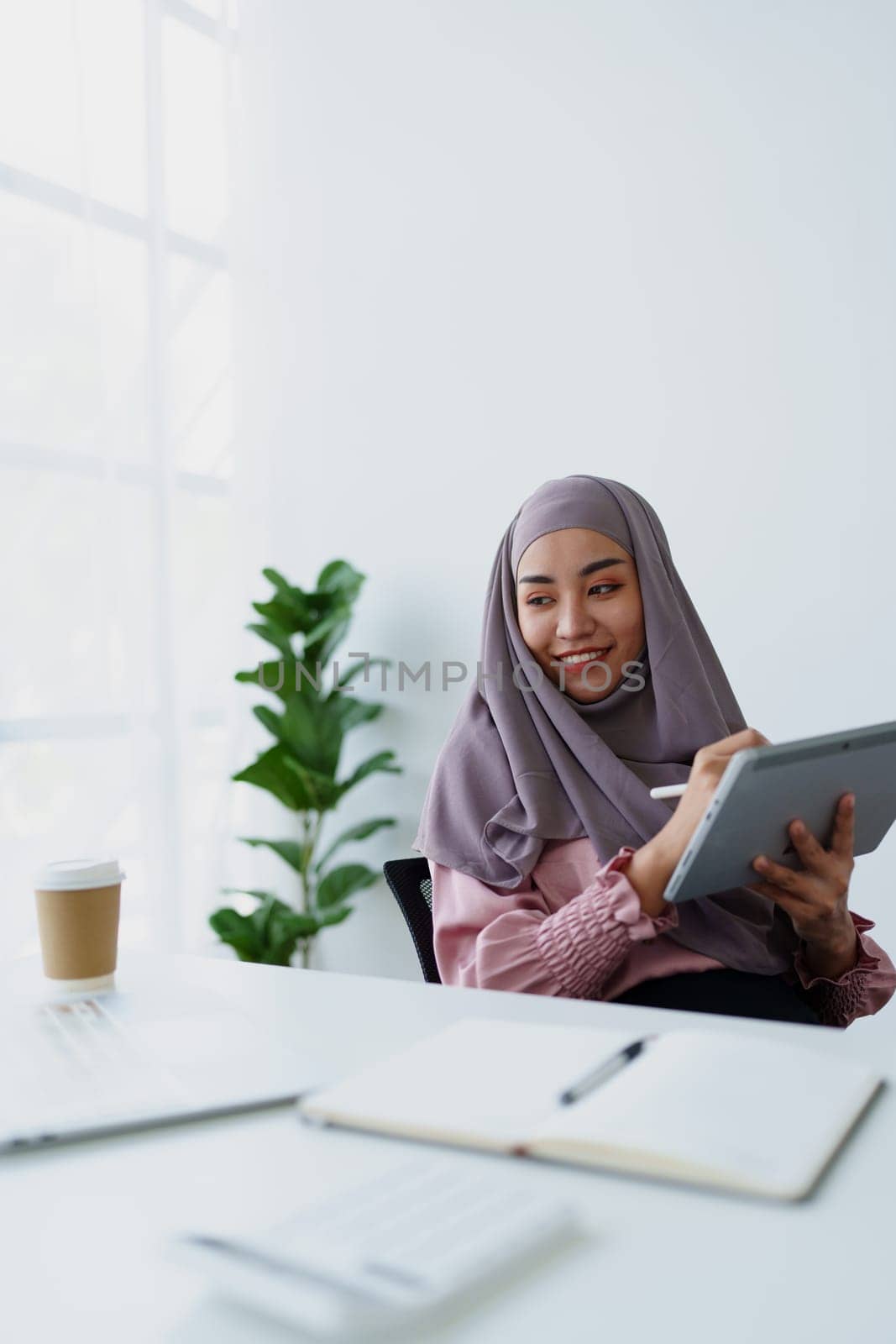 Muslim women use tablet computers, and laptops to check their accounts at work