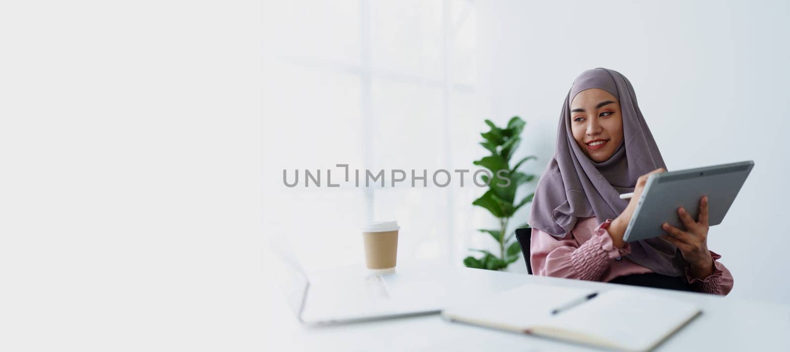 Muslim women use tablet computers, and laptops to check their accounts at work