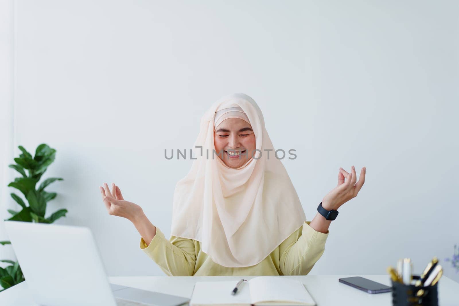 Muslim female employee Meditate while working in the office. by Manastrong