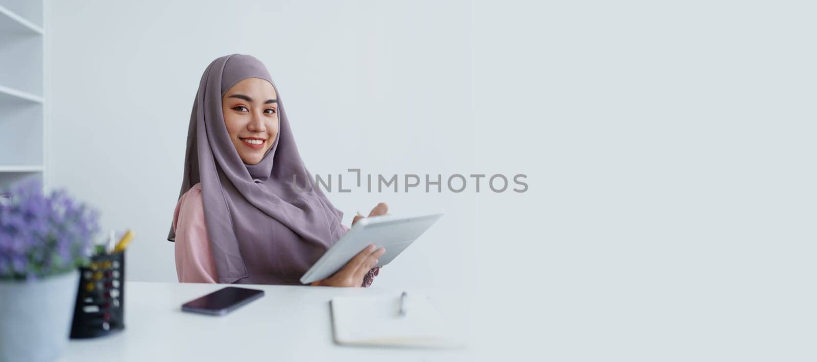 Muslim women use tablet computers, and laptops to check their accounts at work