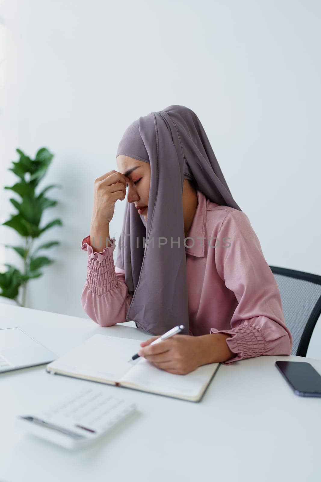 Muslim female employee working in office burnout. by Manastrong