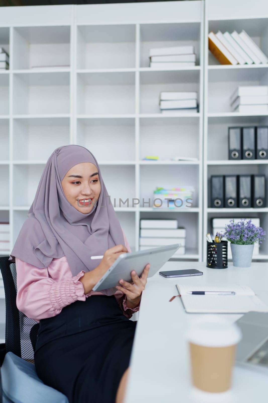 Muslim women use tablet computers, and laptops to check their accounts at work. by Manastrong