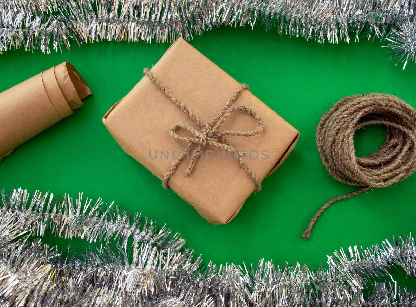 New Year holiday background. Gift, twine and paper and tinsel on a green background. Background for advertising.
