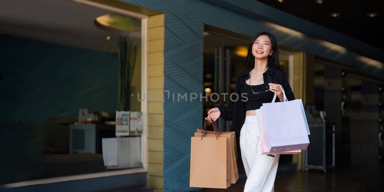 Happy beautiful young stylish woman asian with shopping bag while walking in the mall on holiday Black Friday by nateemee