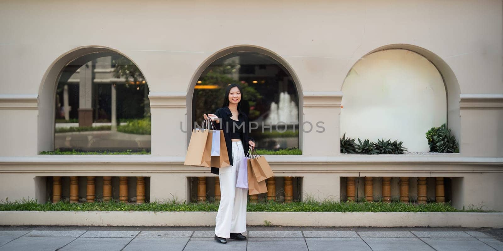 Happy beautiful young stylish woman asian with shopping bag while walking near mall on holiday Black Friday.