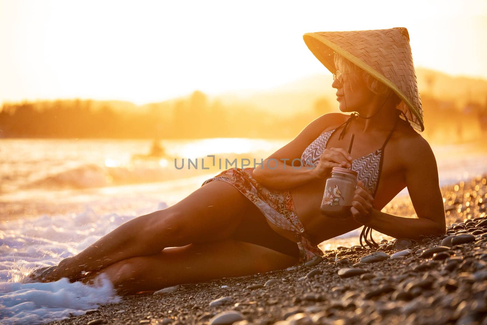 beautiful girl with a smoothie by the sea in a straw Asian triangular hat by Rotozey
