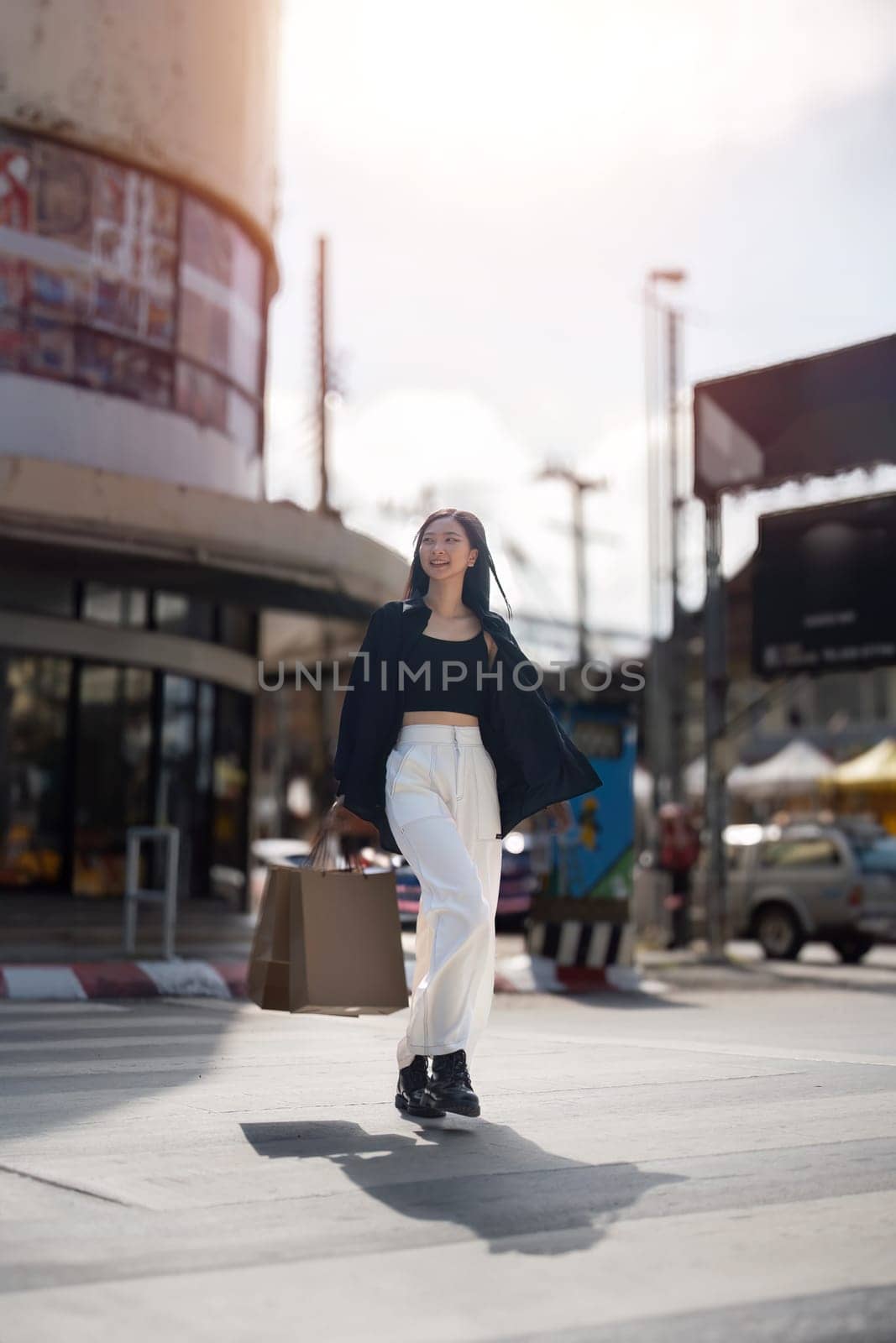 Happy beautiful young stylish woman asian with shopping bag while walking middle of the road on holiday Black Friday.
