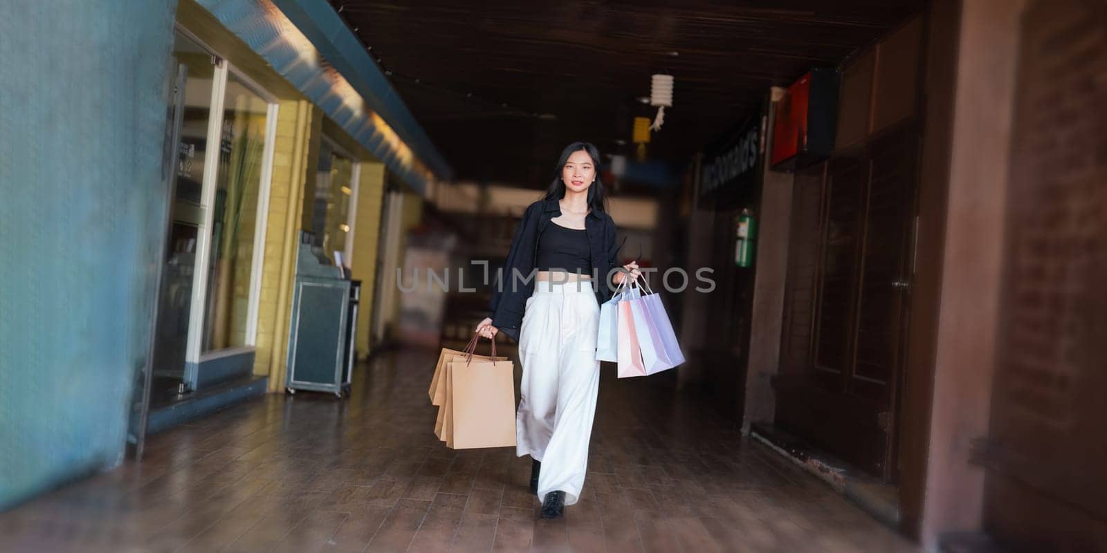 Happy beautiful young stylish woman asian with shopping bag while walking in the mall on holiday Black Friday.