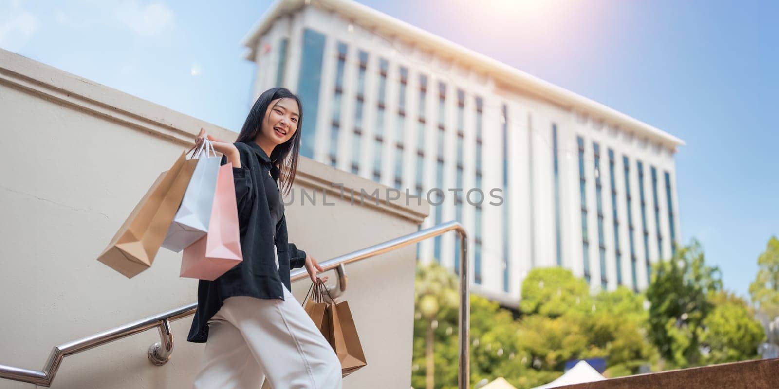 Happy beautiful young stylish woman with shopping bag while walking come out of mall on holiday Black Friday by nateemee