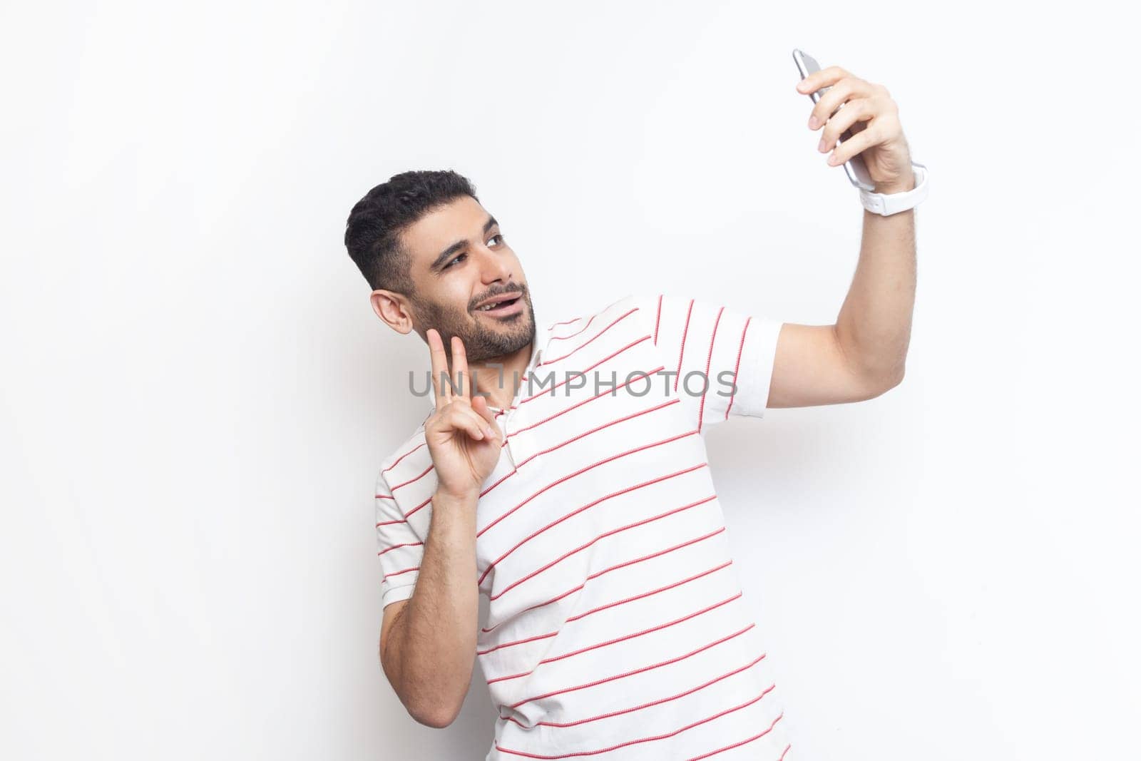 Joyful handsome playful man standing making selfie, showing v sign to his followers. by Khosro1