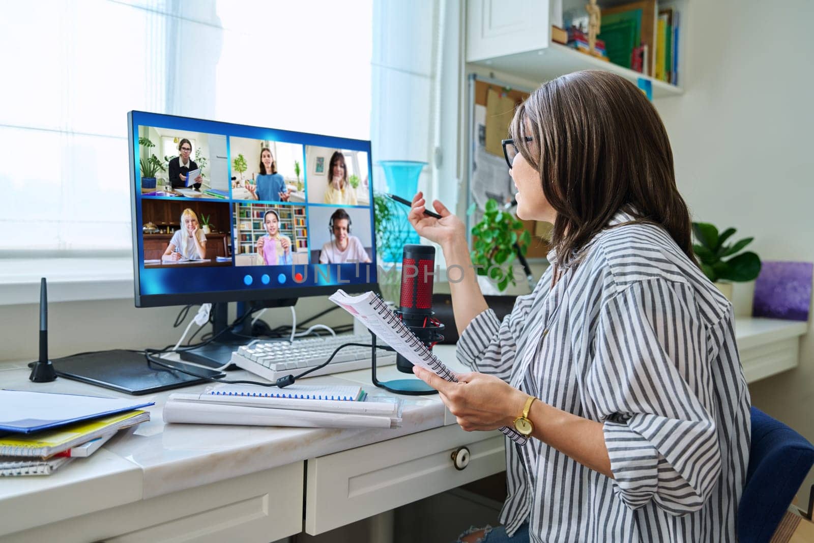 Female teacher working at home remotely, online lesson with group teenage students, teaching looking at computer screen sitting at home. Distance virtual class course interactive lesson video conference