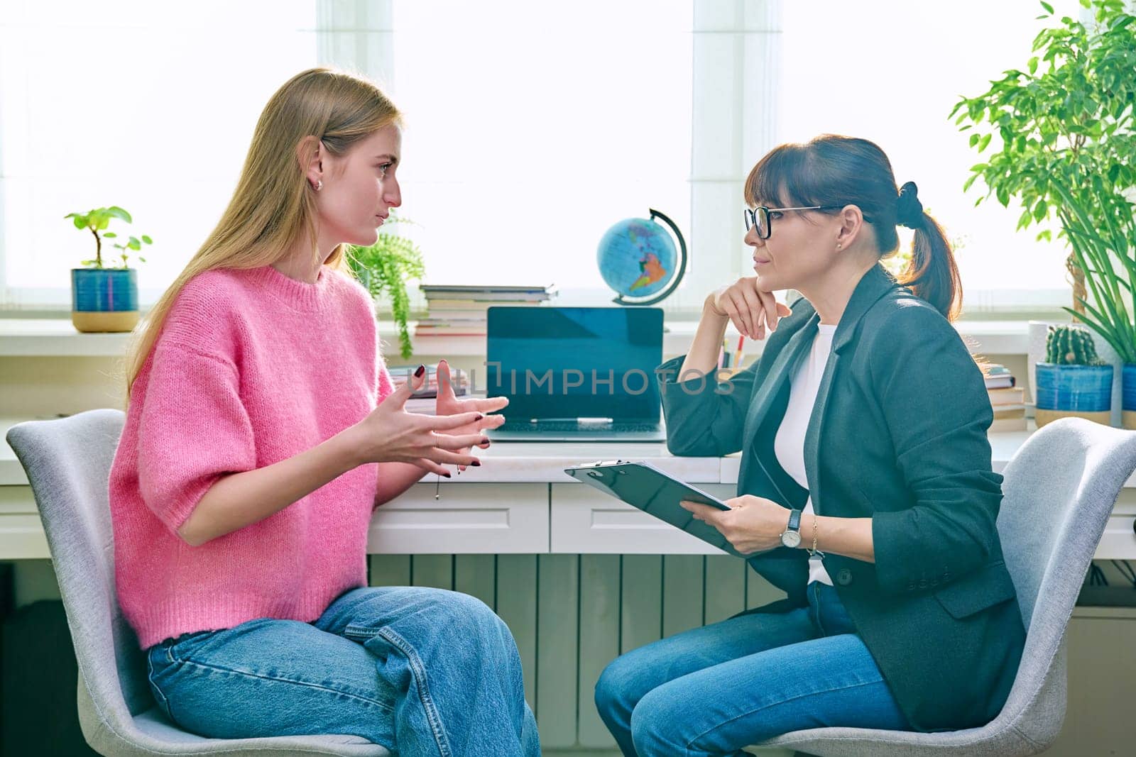 Female psychologist therapist working with young teen girl sitting in office. Teenage female student at therapy meeting with counselor. Psychology therapy psychotherapy youth mental health treatment