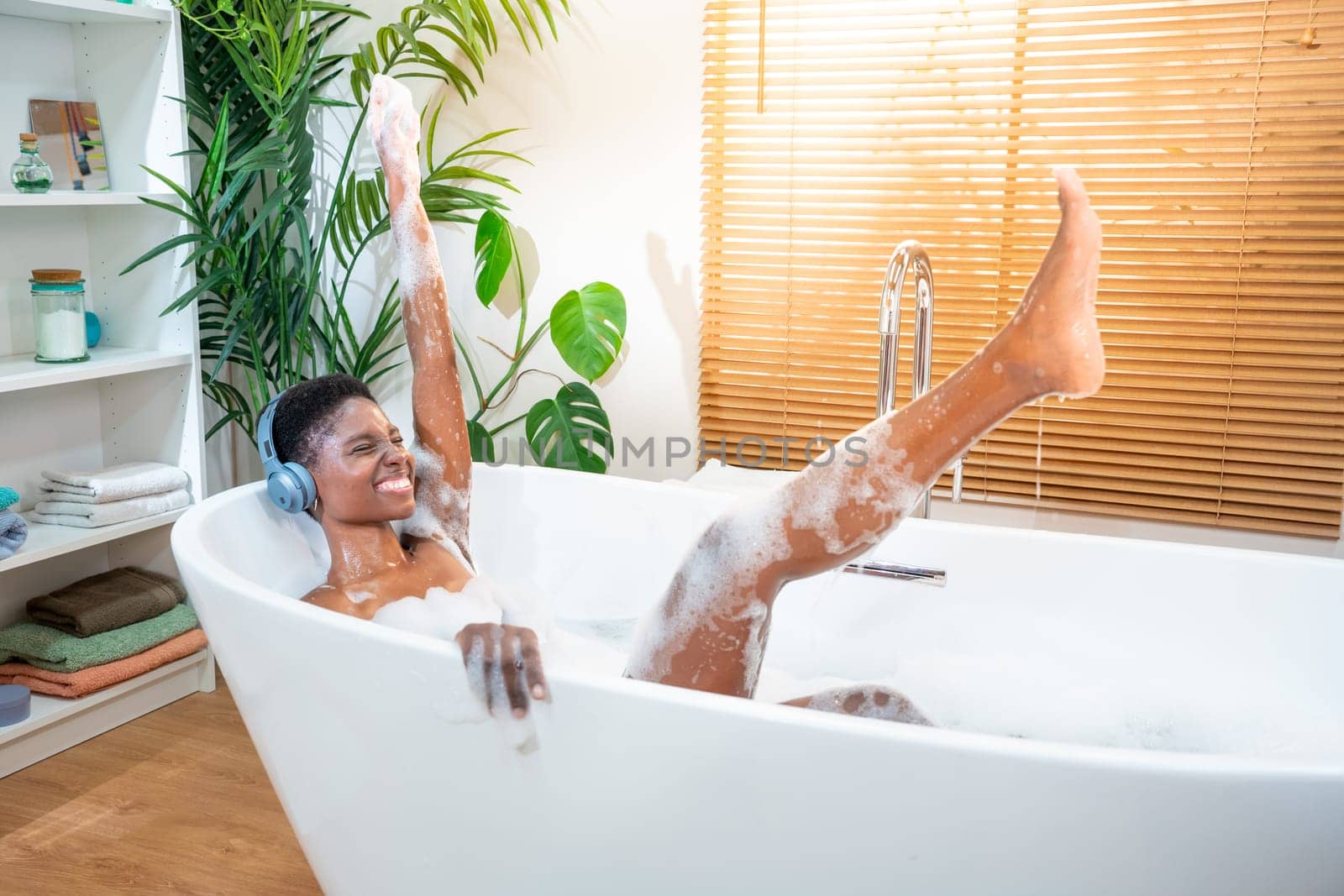 Attractive black woman wearing headphones with music in foam bathtub. by PaulCarr