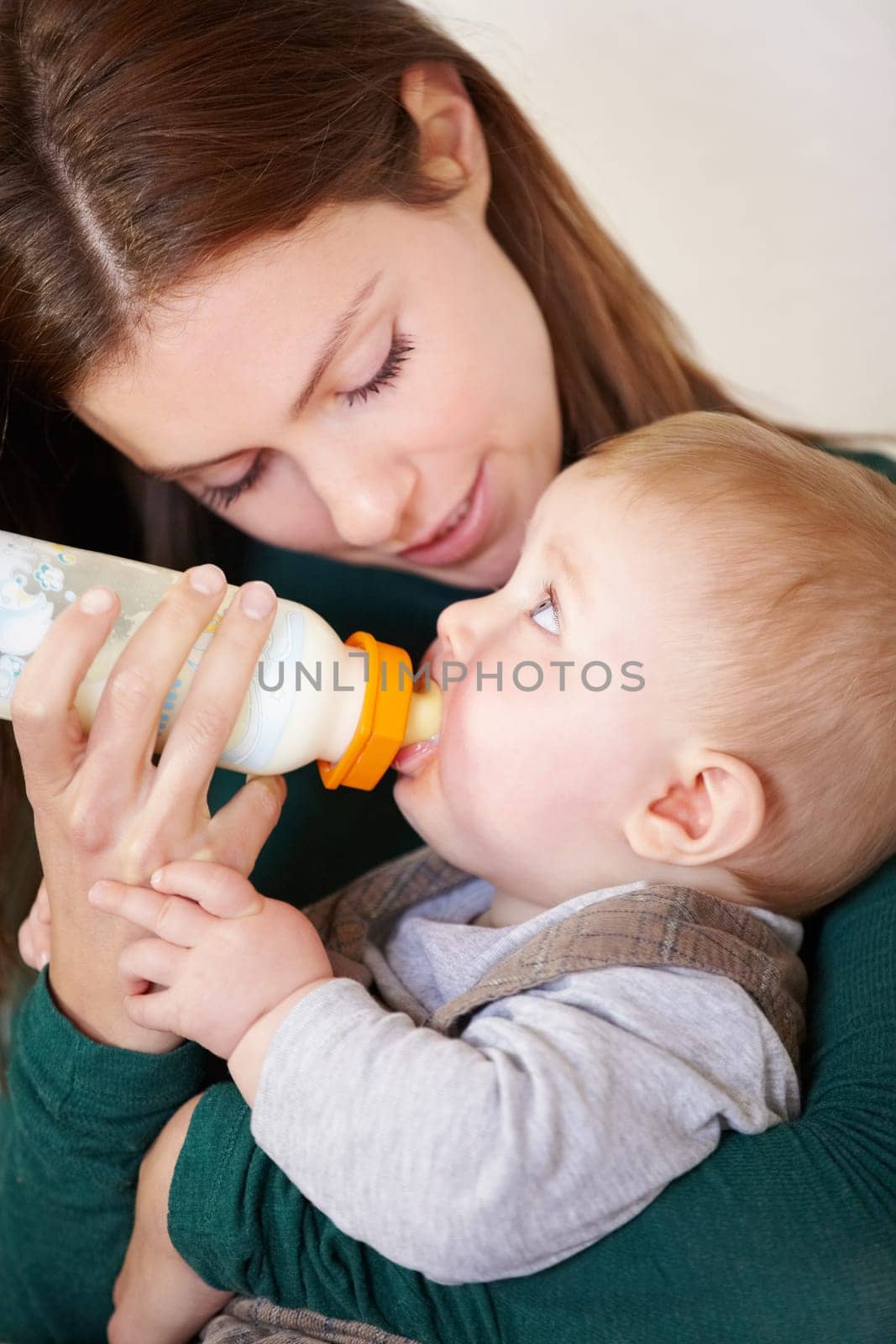 Woman, holding and baby with bottle for feeding in home for growth, child development or hunger. Mother, son and bond by looking at boy for formula, food or milestone in nutrition, health or diet by YuriArcurs