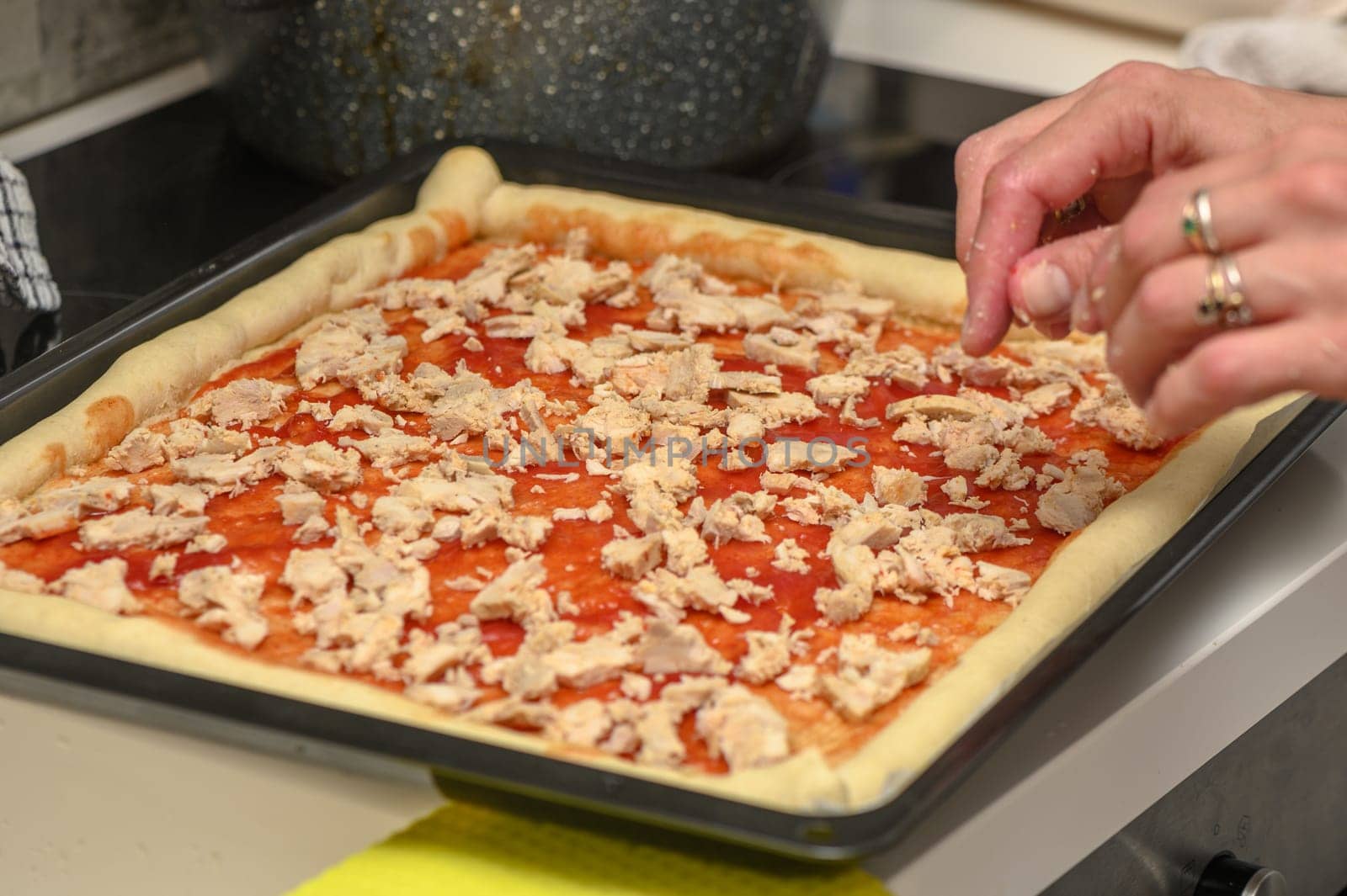 a woman prepares pizza with cheese, tomatoes and chicken ham, a woman lays out chicken ham 3