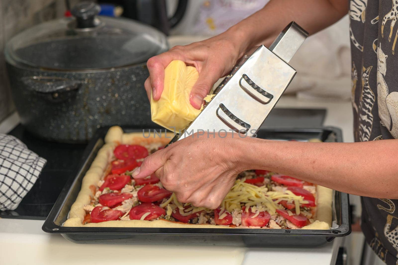 woman prepares pizza with cheese, tomatoes and chicken ham, woman rubs cheese 1