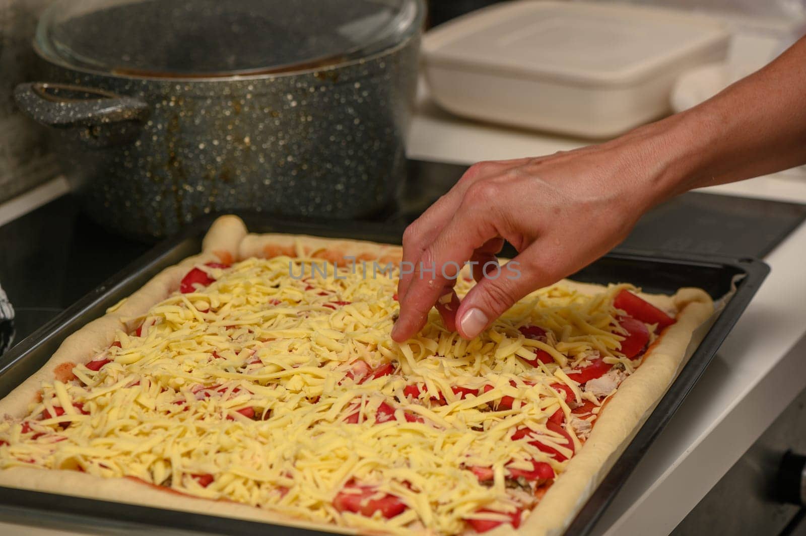 woman prepares pizza with cheese, tomatoes and chicken ham, woman rubs cheese 17