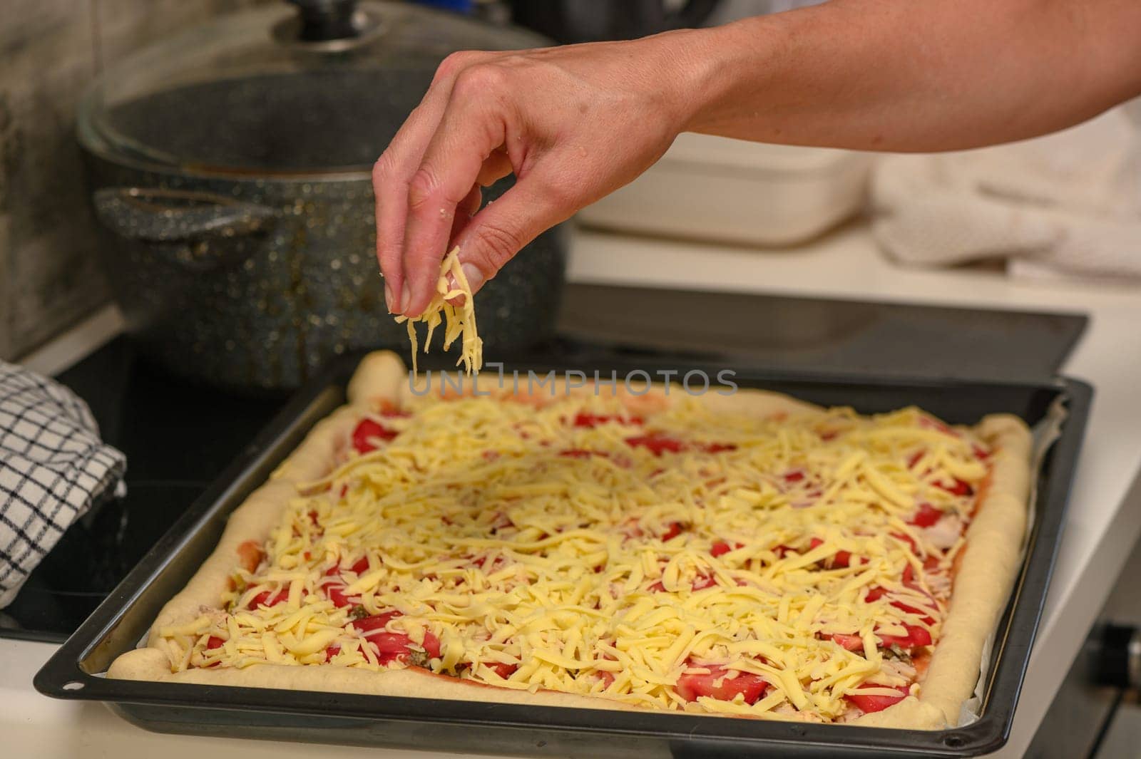 woman prepares pizza with cheese, tomatoes and chicken ham, woman rubs cheese 20