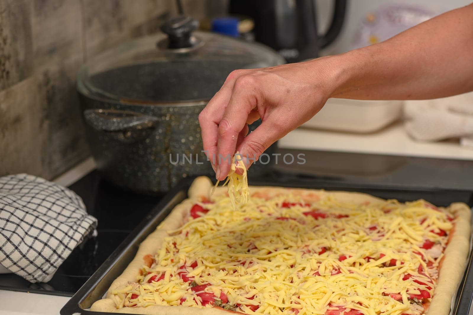 woman prepares pizza with cheese, tomatoes and chicken ham, woman rubs cheese 19