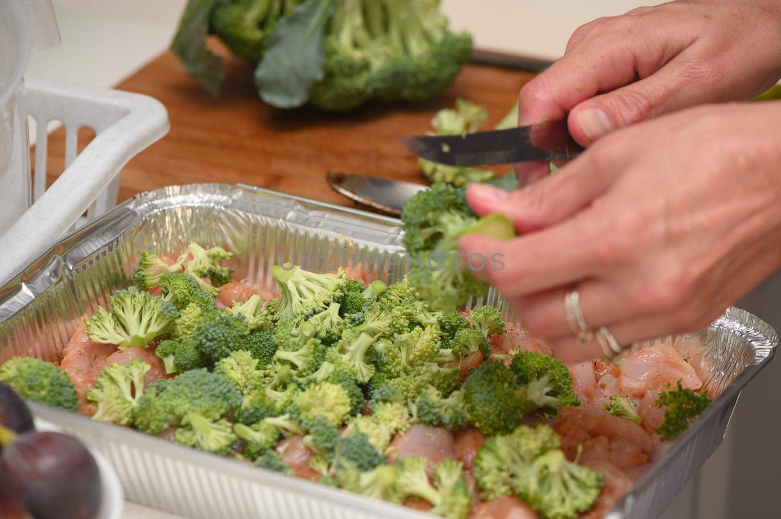 woman cutting broccoli into chicken fillet for baking 10