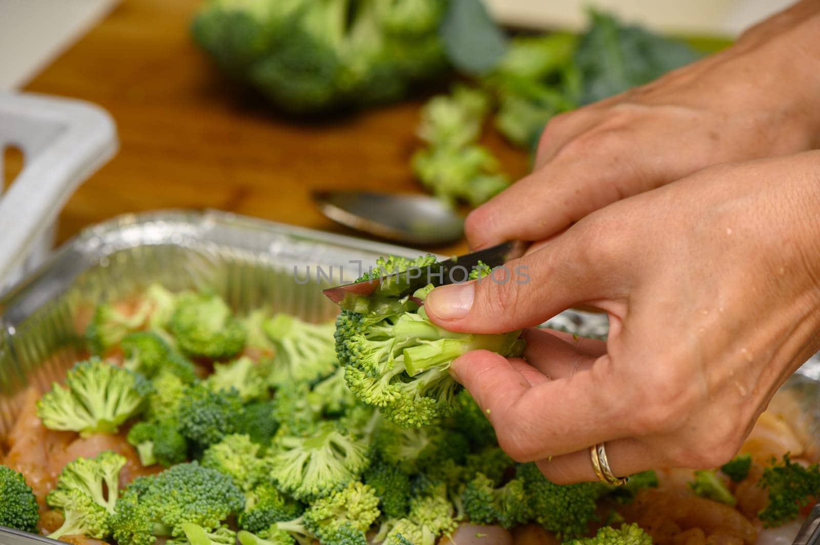 woman cutting broccoli into chicken fillet for baking 6