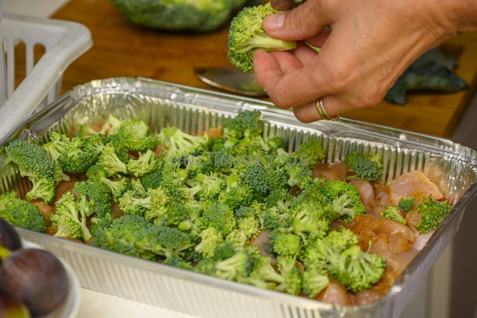 woman cutting broccoli into chicken fillet for baking 2