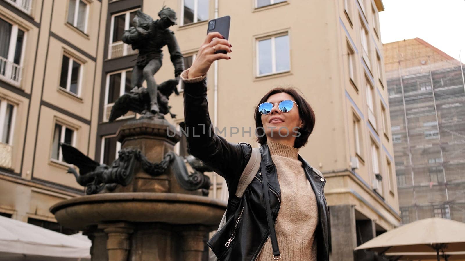 Stylish Woman Strolls Through Historical Touristic Streets In Dresden, Capturing Images Of Monument