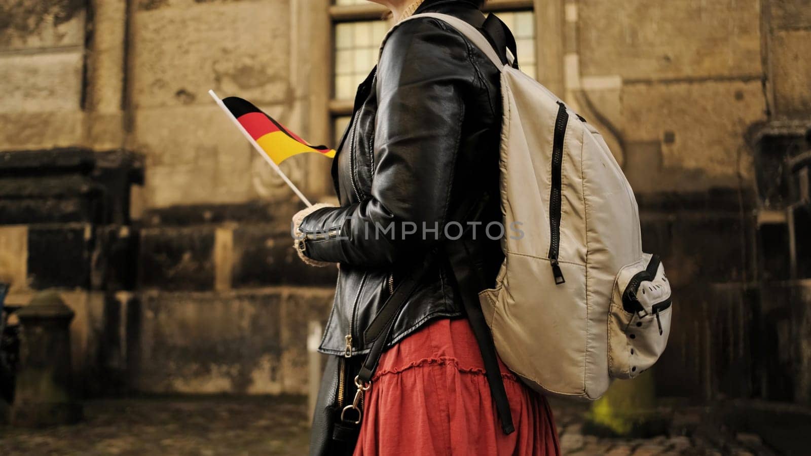 Attractive Female Tourist With Germany Flag Walks In Historical Center Of Dresden Carrying Backpack