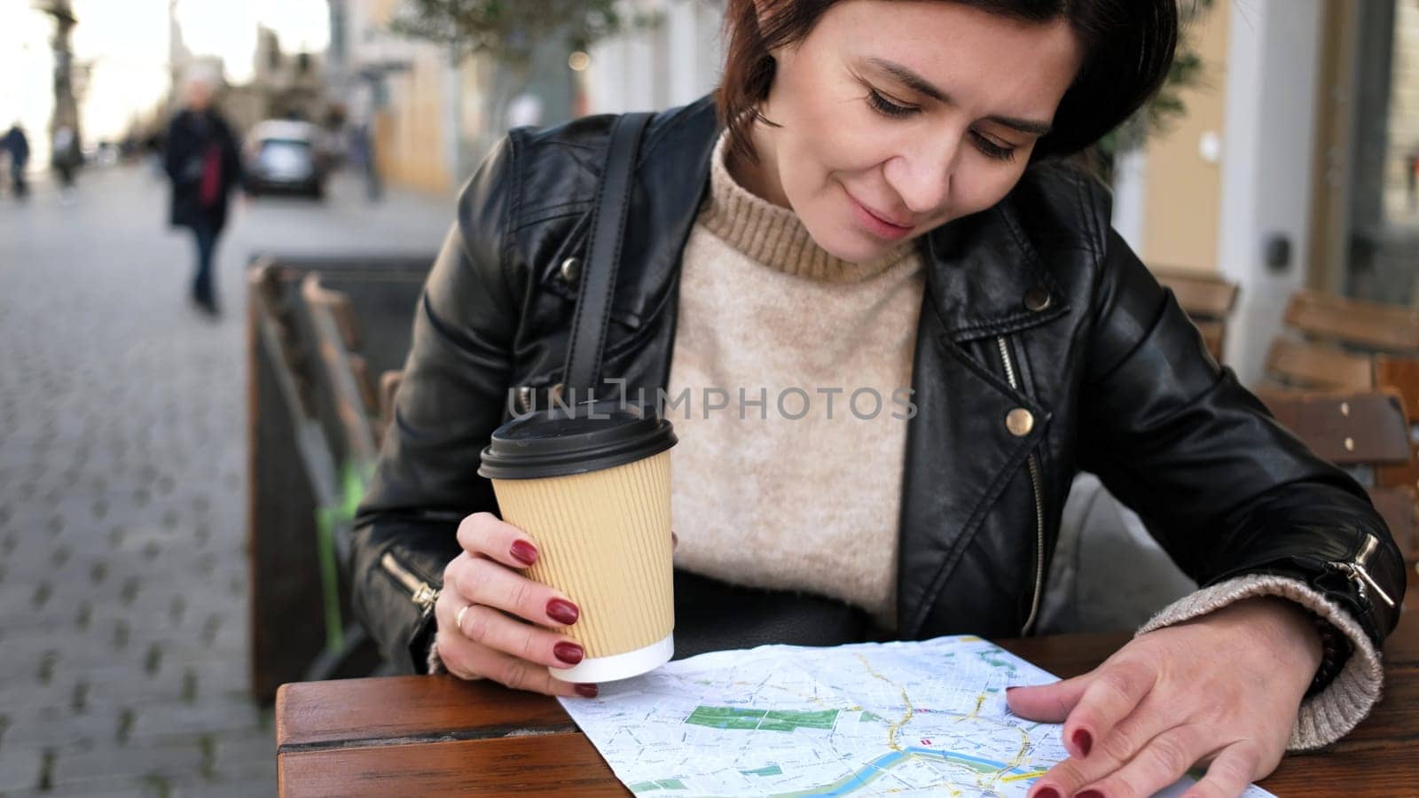 Stylish Female Tourist Checks City Sightseeing Route On Map While Sipping Coffee In Street Cafe