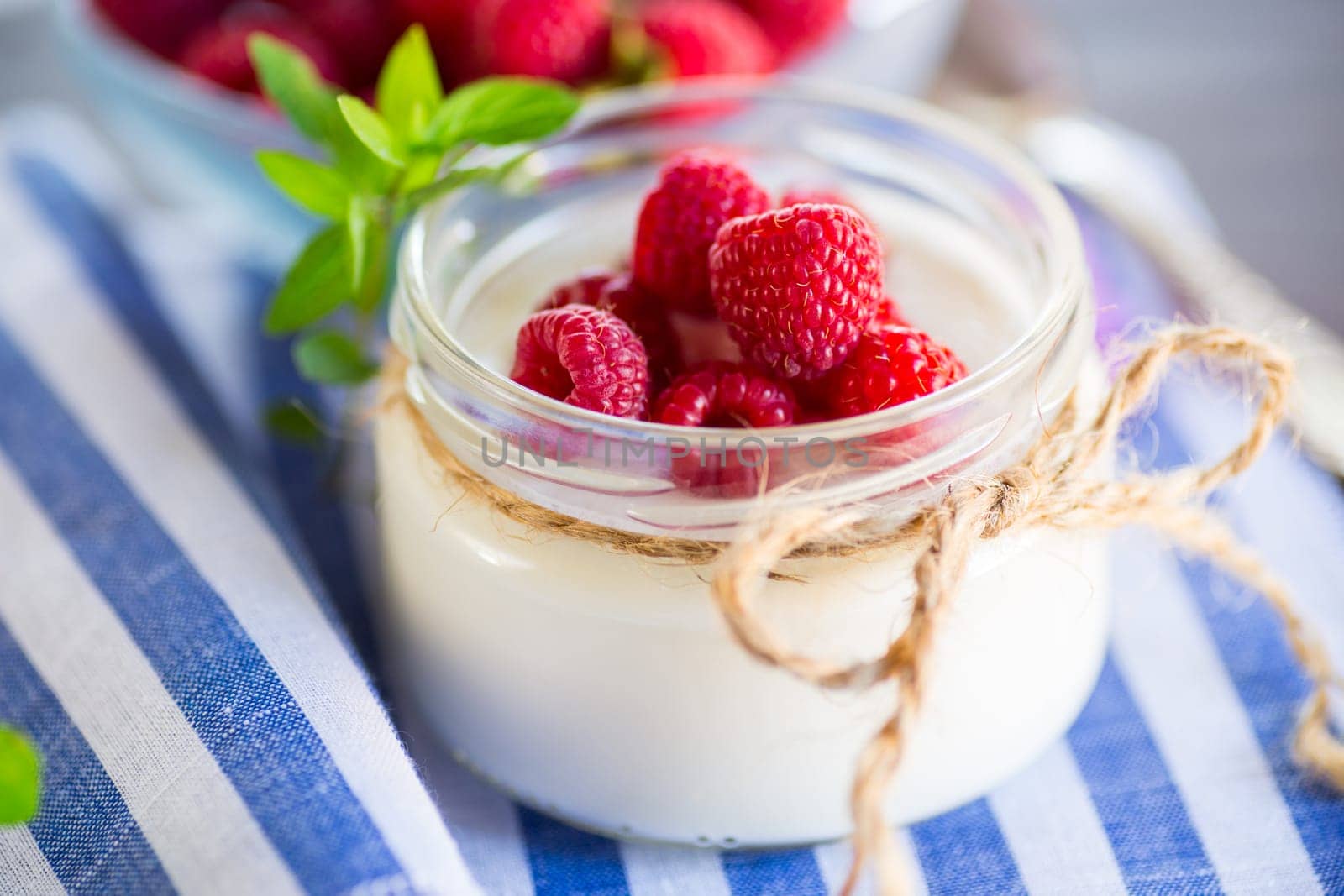 Sweet cooked homemade yogurt with fresh raspberries in a glass jar. by Rawlik