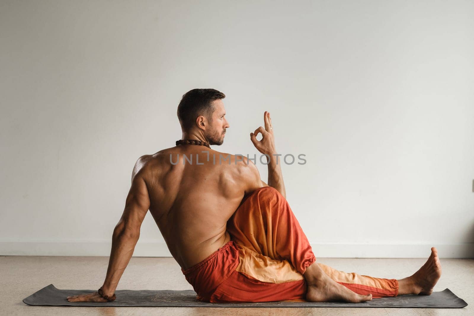 a man with a naked torso does yoga indoors. Fitness Trainer by Lobachad