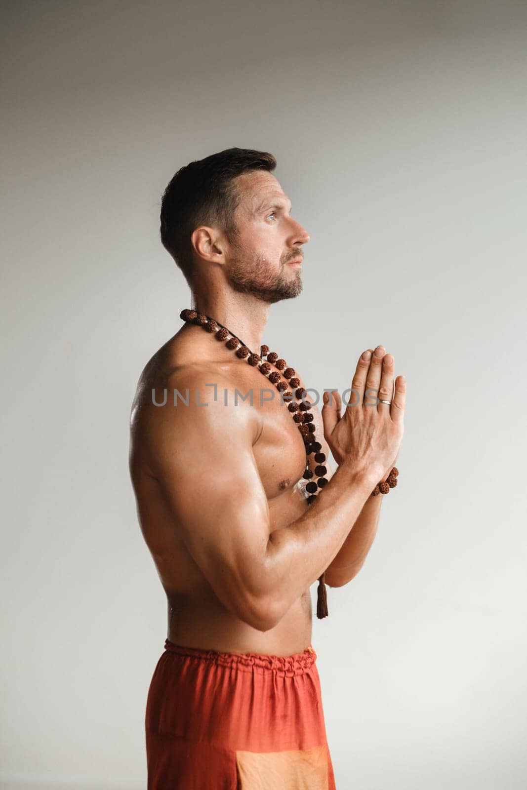 A muscular man with a bare torso and an amulet is standing in the room.