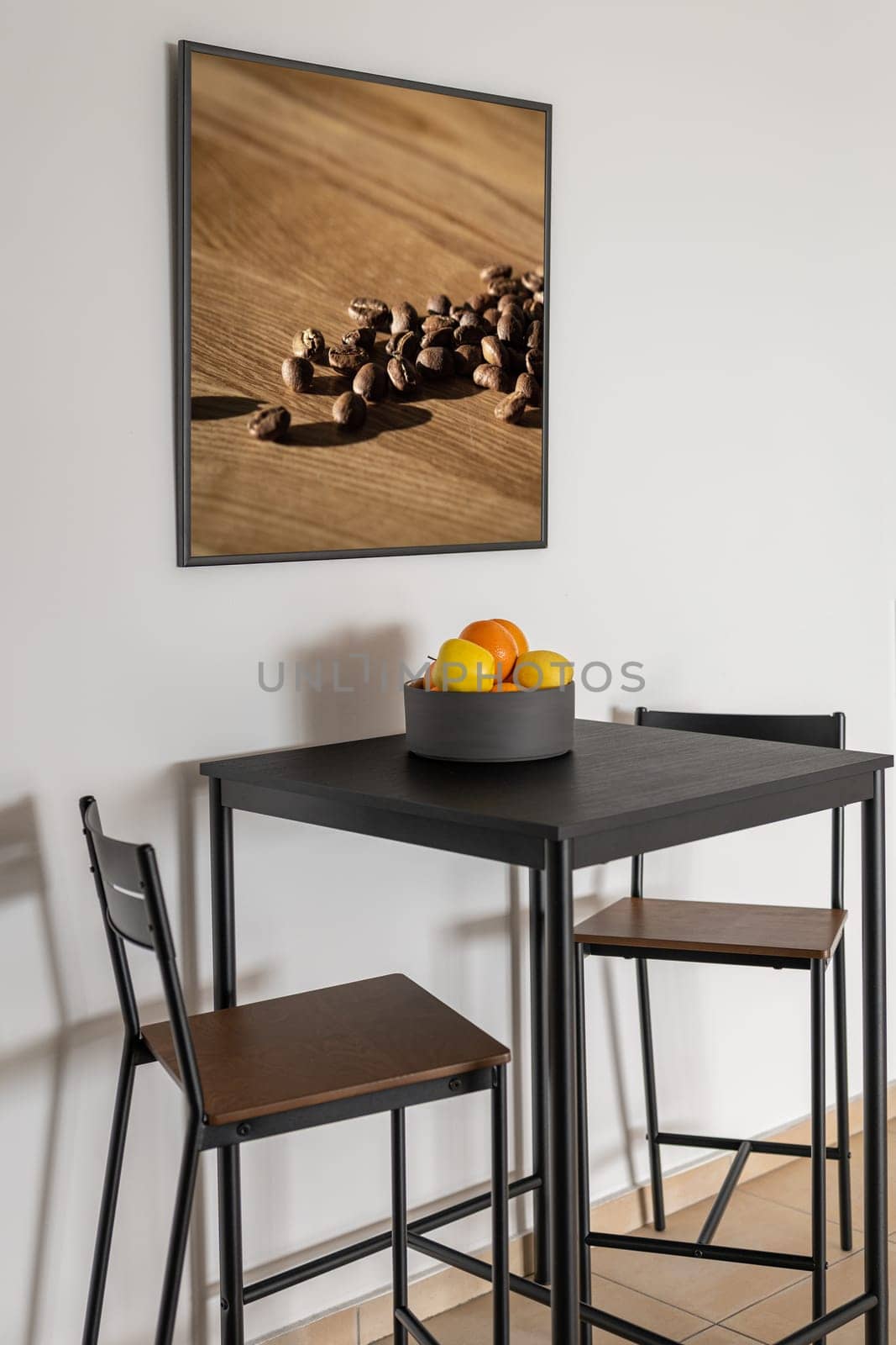 High bar table with chairs and fruits in bowl near white wall by apavlin